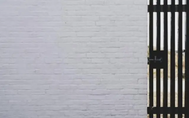 Black metal gate set in a painted white brick wall