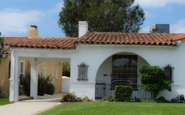 White stucco home with a red tile roof and an arched entry