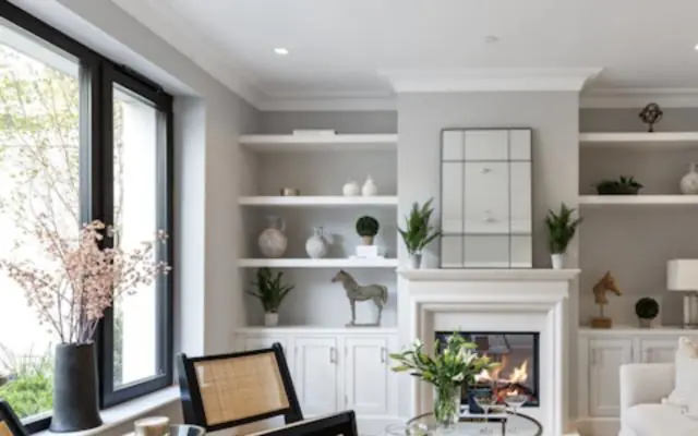 Bright living room with white built-in shelves, crown molding and a fireplace